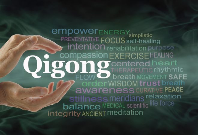 Qigong  word  cloud  and  healing  hands  -  female  cupped  hands  with  the  word  QIGONG  between  surrounded  by  word  cloud  on  a  flowing  green  light  and  dark  background